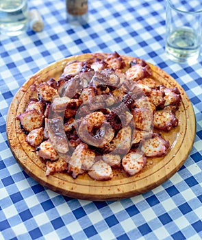 Wooden plate of galician cooked octopus with paprika and olive o photo