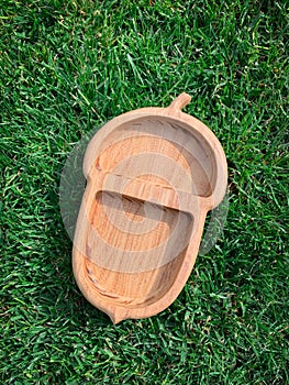 Wooden plate on green grass background