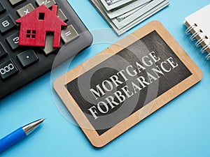 Wooden plate with inscription mortgage forbearance and model of house.