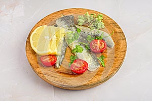 Wooden plate with marinated sardines and garnish.