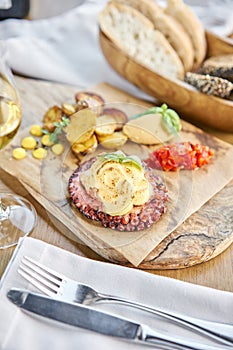 Roasted octopus BBQ and Baked potato with a glass of Grapa. Wooden plate. Restaurant menu photo