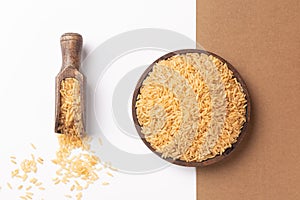 Wooden plate and spoon with brown rice, on  white and brown background. Flat lay composition