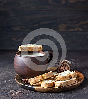 Wooden plate with traditional Italian cookies and a cup of coffee. Biscotti or cantucci with almond and raisin. Brown stone