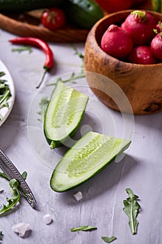 Wooden plate with vegetables for a vegetarian salad on white textured background, close-up, selective focus