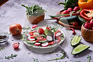 Wooden plate with vegetables for a vegetarian salad on white textured background, close-up, selective focus