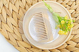 Wooden plate with wooden hairbrush and linden (tilia, basswood, lime tree) flowers. Natural hair care, homemade spa