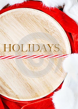 Wooden Plate with Wording Holidays on Christmas Concept Background