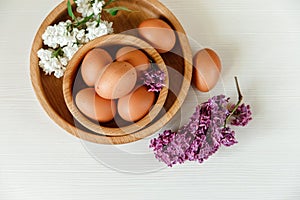 Wooden Plates with Eggs,White and Purple Branches of Lilac.White Wooden Background.Top View,Croped