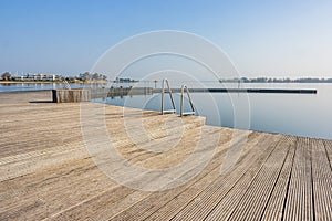 Wooden platform or atoll with metal stairs in natural swimming pool at Woldstrand Zeewolde beach recreation area