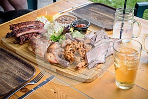 Wooden platter full of delicious smoked meat, sauce and beans