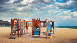Wooden playground for small children on the beach in sunny morning. Sea sunrise