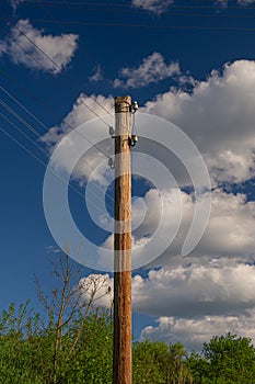 Wooden pole with a power line against a blue sky with clouds