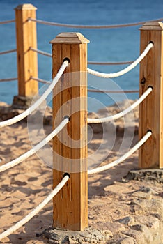 Wooden pole of a rope fence near the sea