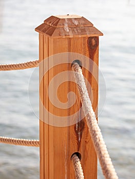 Wooden pole of a rope fence near the sea