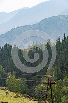 Wooden poles with electrical wires in mountainous region. Spread of electricity to hard-to-reach areas