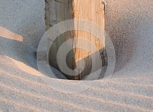 Wooden post buried in the sand