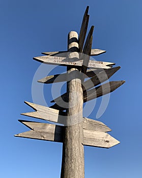 Wooden post with many pointers. There are different signs at the crossroads. There is a signpost for travelers at the crossroads