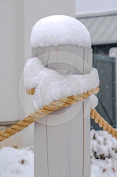 Wooden post with rope topped with snow in winter