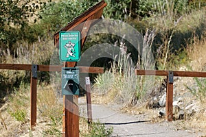 On a wooden post that says & x22;Clean up after your pet& x22; on the side of a dirt trail