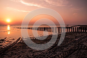 Wooden posts at the beach pictured at sunset