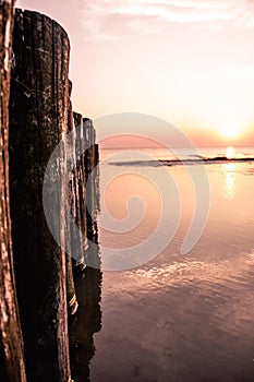 Wooden posts at the beach pictured at sunset