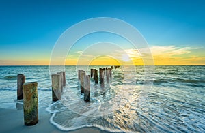Wooden posts on Naples Beach at sunset, Florida