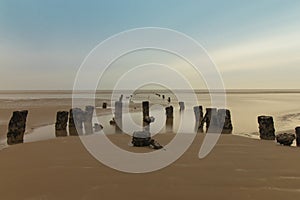 Wooden posts in the sand close to the sea