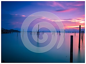 Wooden posts in sea against sky during sunset