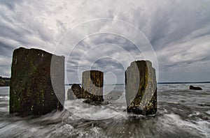 Wooden posts in the shallow ocen water on an overcast day