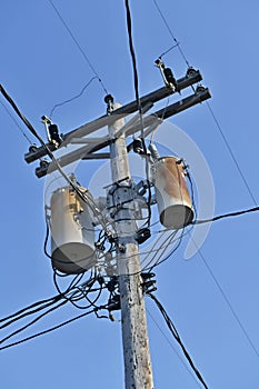 Wooden power utility pole with transformers and cables.