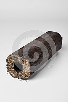 Wooden pressed briquette Pini Kay from biomass on a white