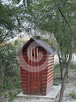 Wooden public toilet on the beach among the trees