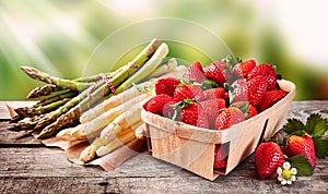 Wooden punnet of strawberries with fresh asparagus photo