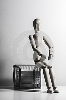 Wooden puppet sitting on a metal box for note sheets