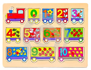 Wooden puzzle in form of train with numbers and arithmetic signs with pictures of items. Children`s hand takes the