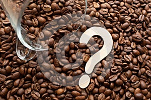 Wooden question mark and glass cup on coffee roasted beans. Flat lay. Top view.