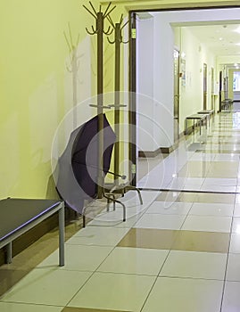 Wooden rack hanger with an open umbrella in an empty room of the corridor of a medical clinic, vertical