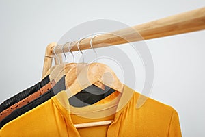 Wooden rack with stylish clothes on light background