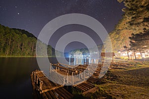 A wooden raft, kayak, or boat in river with stars at night in Pang Ung national park in reservoir, Mae Hong Son, Thailand