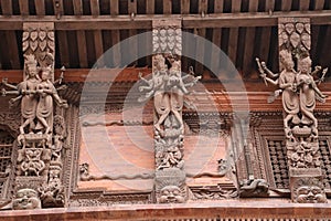 Wooden reapers with elegant carvings of god and and goddess placed in an angles to support the slopped roof of the building in photo