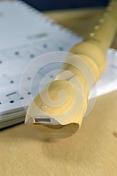 A wooden recorder on sheet music.