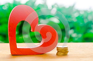 Wooden red heart and a stack of coins. Health care conceptual policy, health financing, research and development have grown