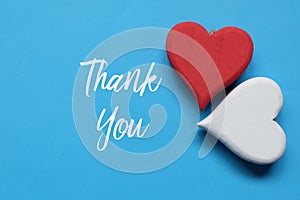 Wooden red and white heart on blue background written with THANK YOU