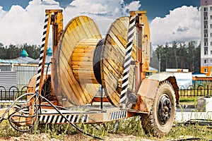 Wooden reel with high voltage cable mounted on a trailer for easy transport and stowage. Laying a high-voltage power cable in the