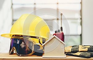 Wooden replicas, yellow helmets and accessories are placed on wooden floors.Standard and safe construction concept.