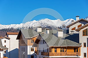 Wooden residential building with sloping roofs in the European style against the backdrop of a mountain snow-capped peak with