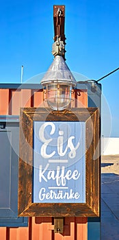 Wooden restaurant sign on the beach. Letter with Kaffee Eis GetrÃ¤nke means Coffee Ice Drinks