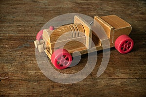 Wooden retro car, children`s toy on a wooden background