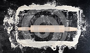 wooden rolling pin on a black background, top view