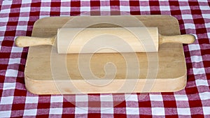 Wooden rolling pin on a board with chequered table cloth